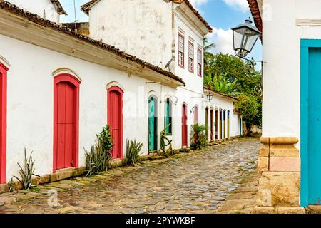 Strada con pavimento in ciottoli e facciate di vecchie case coloniali nella storica città di Paraty, nello stato di Rio de Janeiro, Brasile Foto Stock