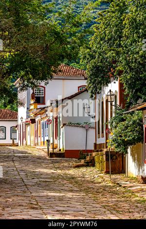 Pendenza con pavimento in pietra e vecchie case colorate in stile coloniale nella città di Tiradentes a Minas Gerais, Brasile Foto Stock