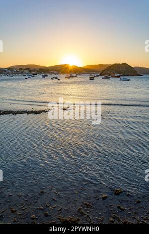 Tramonto dietro le colline e riflesso nelle acque marine della città di Buzios sulla costa nord di Rio de Janeiro, Brasile Foto Stock