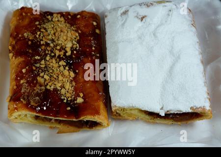 Torta di mele farcita con mela cremosa, cannella e sciroppo di miele dolce zuccherato e sormontata con pistacchi, noci e zucchero a velo, delizioso dolcificato al forno Foto Stock