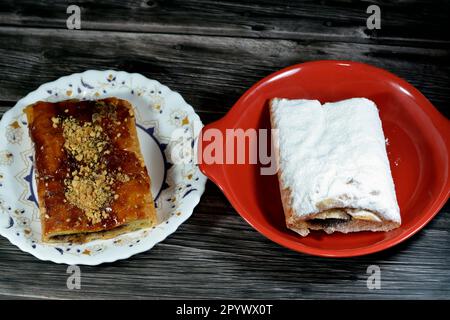 Torta di mele farcita con mela cremosa, cannella e sciroppo di miele dolce zuccherato e sormontata con pistacchi, noci e zucchero a velo, delizioso dolcificato al forno Foto Stock