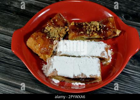 Torta di mele farcita con mela cremosa, cannella e sciroppo di miele dolce zuccherato e sormontata con pistacchi, noci e zucchero a velo, delizioso dolcificato al forno Foto Stock