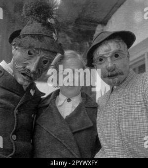 Una donna tra due uomini che indossa maschere di legno intagliate a mano e ornate (colpo non datato). Foto Stock