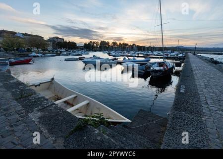 Pittoresco Lago Bolsena al tramonto: Serate tranquille a Bolsena con barche che si tuffano dolcemente sull'acqua calma mentre il tramonto dipinge il cielo con colori caldi Foto Stock