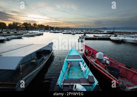 Pittoresco Lago Bolsena al tramonto: Serate tranquille a Bolsena con barche che si tuffano dolcemente sull'acqua calma mentre il tramonto dipinge il cielo con colori caldi Foto Stock