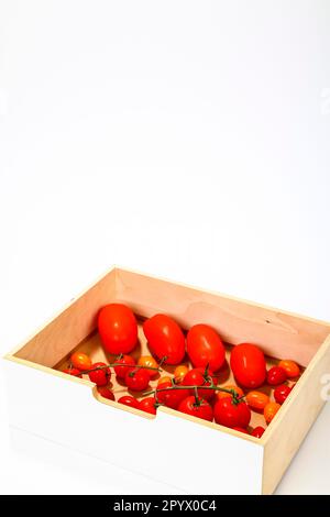 Uva di prugna e pomodori ciliegini in una scatola di legno isolata su uno sfondo bianco Foto Stock