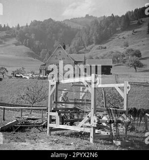 Una donna lavora su un telaio di fronte al mulino di tessitura. Foto Stock