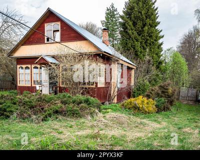 vista del cottage in legno nel villaggio sul cortile coltivato in primavera Foto Stock