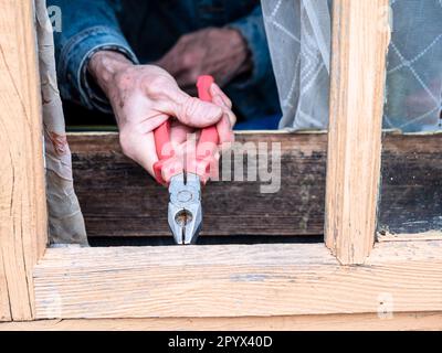riparazione di serramenti in legno in casa rurale con pinze primo piano Foto Stock
