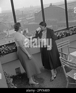 Foto non datata di due donne sulla terrazza sul tetto del Cafe Europa nella Casa d'Europa ad Askanischer Platz a Kreuzberg (Berlino) nell'estate del 1936. Le due Signore fanno una cura medica dell'acqua. Tengono tazze di porcellana bianca con acque curative nelle mani. Sullo sfondo, la facciata principale del distrutto Anhalter Bahnhof nel 1945 (vista a sud). Foto Stock