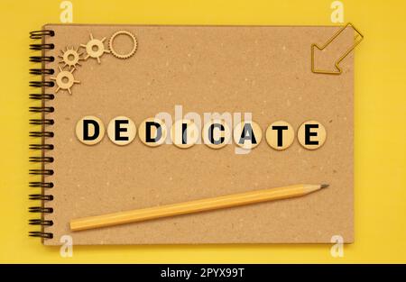 Testo DEDICATO al blocco di cubi di legno, concetto di investimento in stock. Il testo DEDICATO è scritto sui cubi in lettere nere, i cubi si trovano su una b Foto Stock