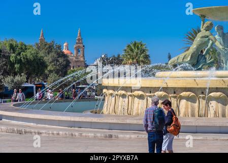 Iconica fontana Tritone di fronte alla porta della città di la Valletta, capitale di Malta Foto Stock