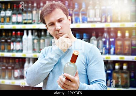 L'uomo sceglie una bottiglia di vodka nel negozio Foto Stock