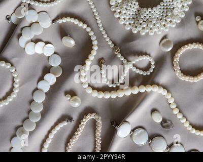 Molti gioielli di perle differenti su uno sfondo beige. Foto Stock