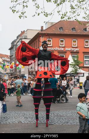 Kaiserslautern, Germania. 5th maggio, 2023. Artista dello Stilt-teatro Circolo vestito con un costume da cocchio che cammina su palafitte davanti ad una folla. Il festival dell'arte di strada si svolge in centro nell'arco di tre giorni. La città di Kaiserslautern ha invitato artisti internazionali di 14 nazioni. Credit: Gustav Zygmund/Alamy News Foto Stock