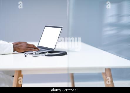 Sezione Centrale Di Male Doctor Using Laptop At Desk In Clinic Foto Stock