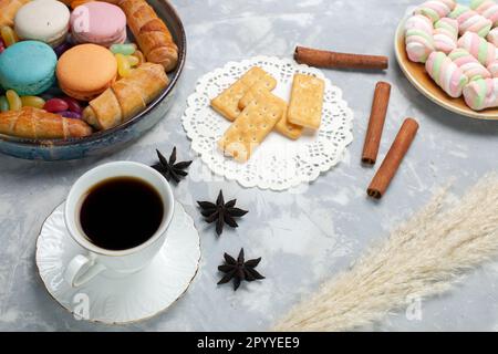 tazza di tè con vista frontale, macaron e bagel sulla scrivania bianca, biscotti dolci al tè Foto Stock