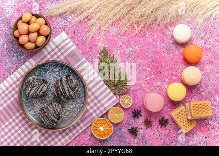 vista dall'alto macaron francesi con torte al cioccolato su sfondo rosa chiaro biscotto torta biscotto torta zucchero dolce Foto Stock