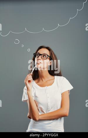 Stato d'animo ritratto di una giovane donna isolato su uno sfondo neutro. La ragazza premurosa guarda in su, immaginando, inventando. Braccia incrociate, penna a bocca w Foto Stock