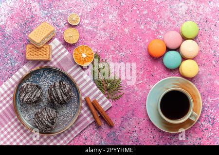 vista dall'alto dolci al cioccolato con tazza di tè e macaron francesi su sfondo rosa zucchero biscotto torta biscotto torta dolce Foto Stock