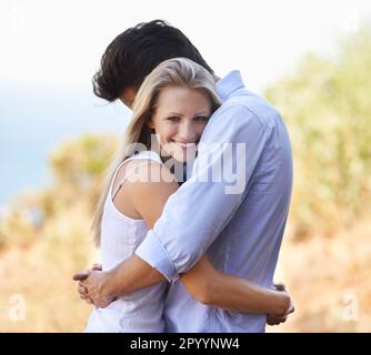 Sicuro tra le braccia. Vista laterale di una giovane coppia che ama abbracciare intimamente all'aperto. Foto Stock