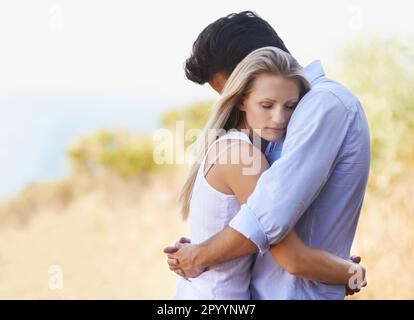 Fissare tra le braccia. Vista laterale della giovane coppia amorevole abbracciandosi intimamente mentre si levano in piedi fuori. Foto Stock