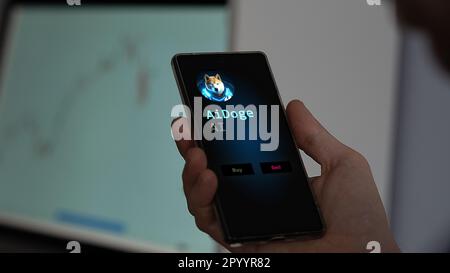 Maggio 2nd 2023. Un investitore che analizza il gettone Aidoge prezzo su uno schermo del telefono, guardando la cripto di $ ai su uno scambio. Foto Stock