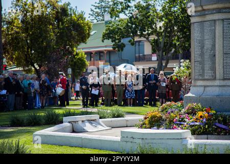 Corone girate intorno alla base del cenotafio commemorativo a Singleton Burdekin Park con la folla che ascolta la cerimonia il giorno ANZAC Foto Stock