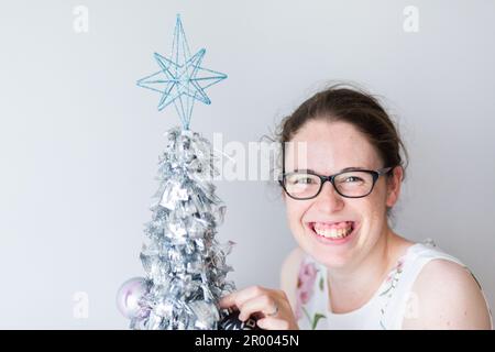 Donna sorridente con mini albero di Natale in argento al chiuso Foto Stock