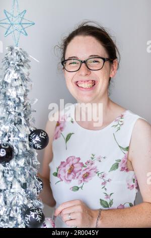 Donna sorridente con mini albero di Natale in argento al chiuso Foto Stock