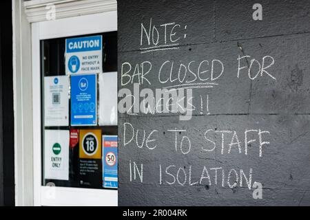 Scrivete gesso sul muro dell'edificio del pub Nota: Il bar è chiuso per 2 settimane a causa del personale in isolamento Foto Stock