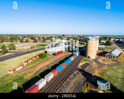 Scena aerea di campagna australiana a Narromine di silos di grano accanto alla ferrovia e al treno merci nelle giornate illuminate dal sole Foto Stock