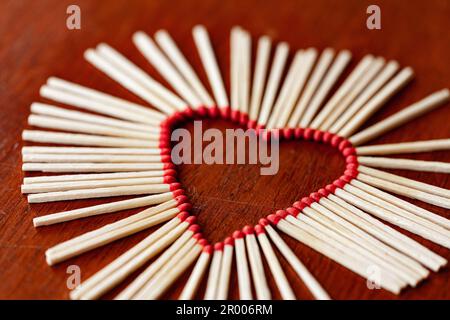 Unlit fiammiferi insieme in forma di cuore pericoloso concetto di amore su sfondo di legno Foto Stock