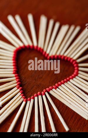 Unlit fiammiferi insieme in forma di cuore pericoloso concetto di amore su sfondo di legno Foto Stock