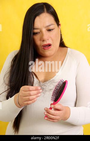 Le mani della donna prendono una spazzola dei capelli con molti capelli caduti dopo la spazzolatura per alopesia, anemia o malattia del postpartum Foto Stock