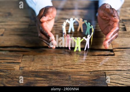 Inclusione, diversità ed uguaglianza. Le mani africane salvaguardano le forme della carta Foto Stock