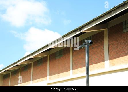 Due telecamere di sorveglianza installate sul palo vicino al magazzino con parete in mattoni. Foto Stock