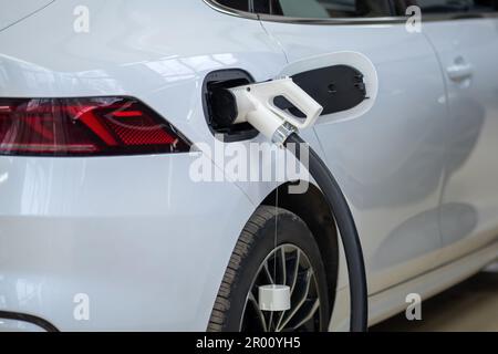 connettore del cavo della stazione di ricarica nella porta di ingresso di un moderno primo piano di un'auto elettrica per passeggeri Foto Stock