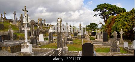 Un antico cimitero cristiano in Irlanda. Pietre tombali in pietra, croce celtica. Cimitero cristiano, cielo nuvoloso Foto Stock