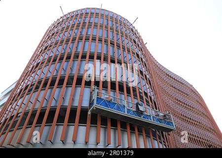 Lavoratore su ponteggi ascensore parete di isolamento facciata del nuovo edificio. Foto Stock