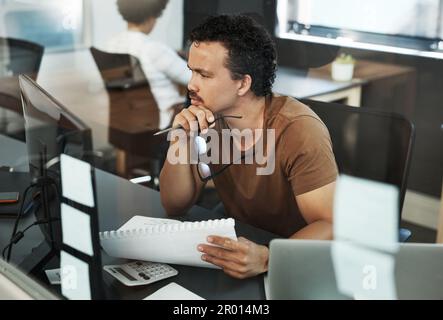 In questo caso sembra esserci un lieve errore. un bel giovane uomo d'affari seduto in ufficio e guardando contemplativo mentre si utilizza il computer. Foto Stock