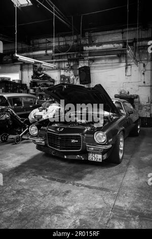 Un vecchio cheverolet con cofano motore aperto si trova in un'officina Foto Stock