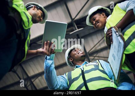 Non hai sempre bisogno di strumenti elettrici per completare le attività di costruzione. Inquadratura ad angolo basso di un gruppo di costruttori che utilizzano un tablet digitale mentre lavorano in una Foto Stock