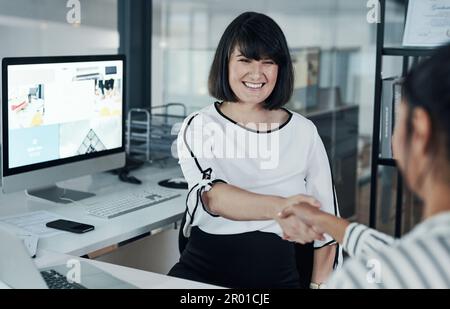 Complimenti per i tuoi progressi. una donna d'affari incinta attraente seduta e che scuote le mani con un collega in ufficio. Foto Stock
