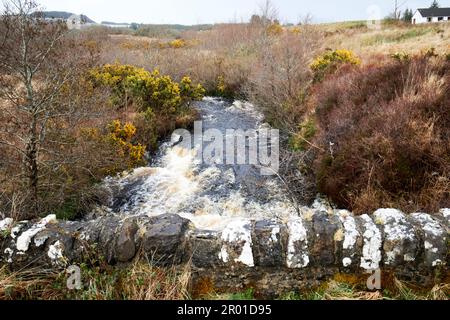 vecchio ponte di pietra sul piccolo fiume torrente in alluvione nella remota regione rurale di montagna della contea donegal repubblica d'irlanda Foto Stock