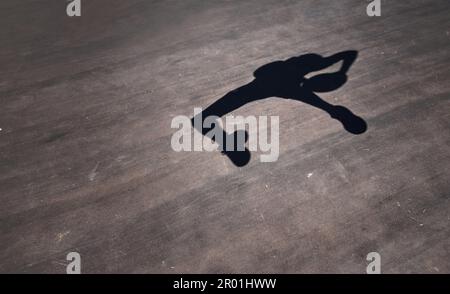 Salta, ruota e gira verso l'anello. l'ombra di un uomo che lancia un basket su un campo sportivo. Foto Stock