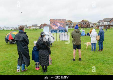 Poole, Dorset, Regno Unito. 6th maggio 2023. Meteo nel Regno Unito. I rivelatori dell'incoronazione che indossano impermeabili e con gli ombrelli sfidano la pioggia per guardare l'incoronazione del re Carlo III su un grande schermo al Parco di Baiter a Poole in Dorset. Picture Credit: Graham Hunt/Alamy Live News Foto Stock