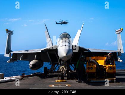 USS Nimitz, acque internazionali. 04 maggio, 2023. NEGLI STATI UNITI Navy MH-60R Sea Hawk Helicopter Maritime Strike Squadron 73 vola oltre un aereo da combattimento F/A-18E Super Hornet sul ponte di volo della portaerei di classe Nimitz USS Nimitz in corso di svolgimento operazioni di routine, 4 maggio 2023 nel Mare delle Filippine. Credit: MC2 Joseph Calabrese/US Navy Photo/Alamy Live News Foto Stock