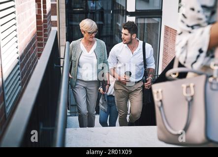 Insieme bene arrivare al top. una donna d'affari e un uomo d'affari che discutono mentre camminano sulle scale in un posto di lavoro moderno. Foto Stock