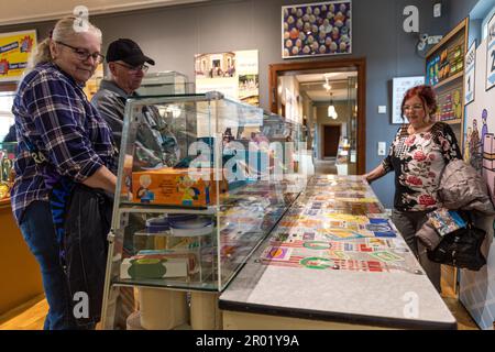 06 maggio 2023, Brandeburgo, Lübbenau: La gente guarda un bancone con prodotti GDR per lo più originali, che si trova in una sala espositiva. La mostra, che si può vedere nel Museo Lübbenau Spreewald fino al febbraio 2024, esplora 'Shopping nella RDT' tra economia pianificata e baratto. Fotografie, imballaggi originali e racconti di esperienze mostrano cosa è diventato un prodotto scarso e quando. Foto: Frank Hammerschmidt/dpa Foto Stock